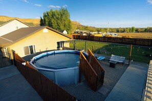 En have med swimmingpool, træterrasse og et hegn.