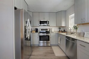 A modern kitchen with stainless steel appliances, light grey cabinetry, and a granite countertop. - Private Zion Stay HotTub~Pool~FirePit~Grill+Views (Colorado City)