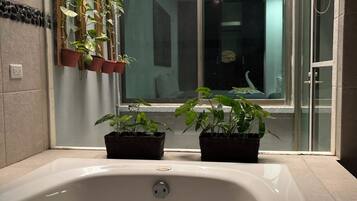 Une salle de bain avec une baignoire, des plantes en pot et une fenêtre.