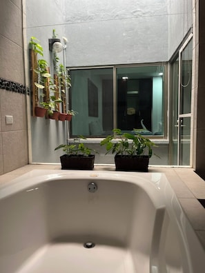 A bathroom with a bathtub, potted plants, and a window. - New Listing (Palenque)