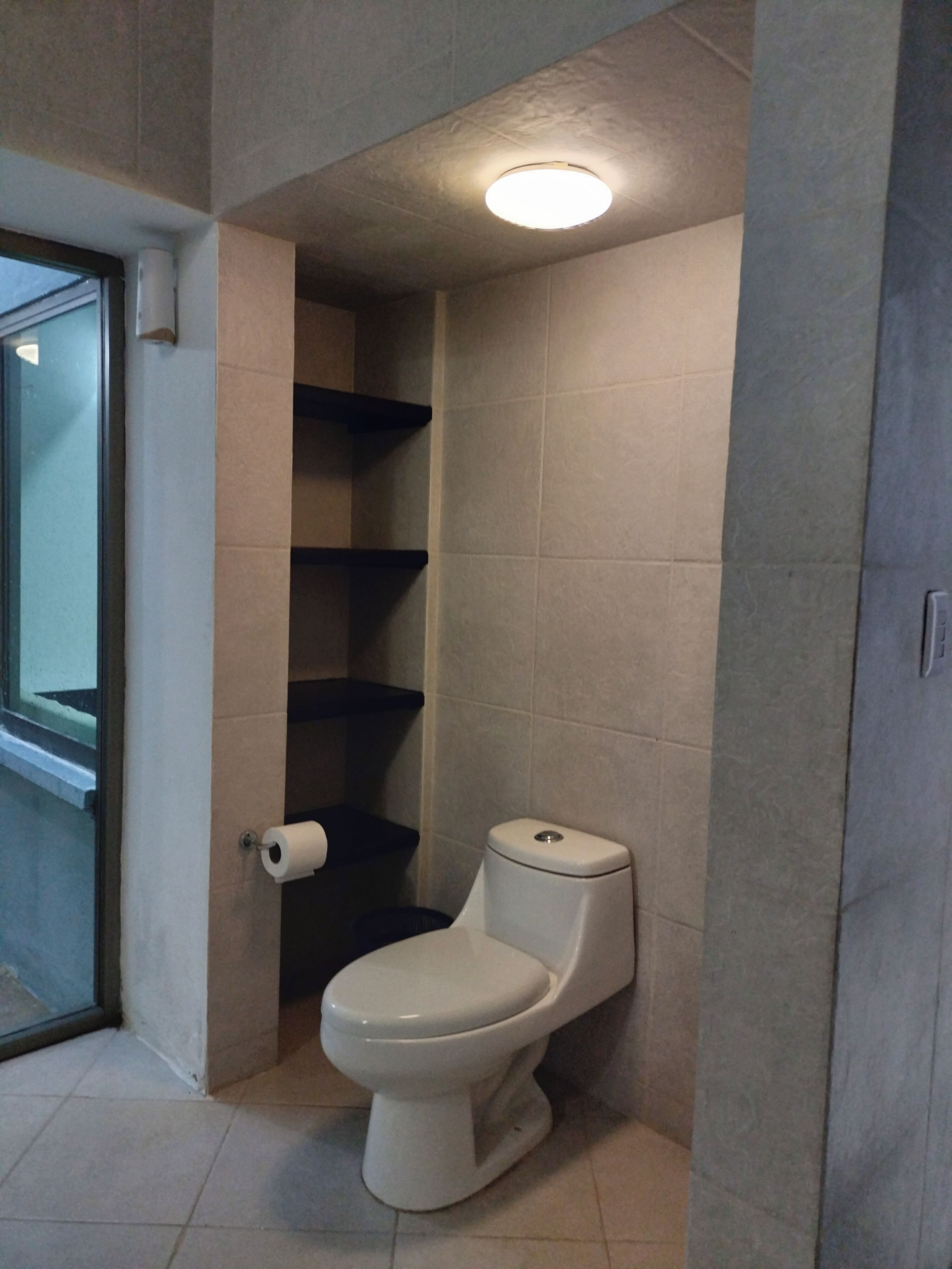 A bathroom with a toilet, a toilet paper holder, and a shower area.