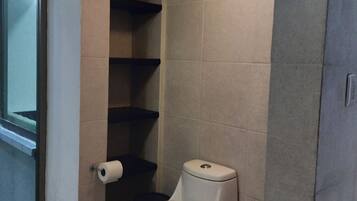 A bathroom with a toilet, a toilet paper holder, and a shower area.