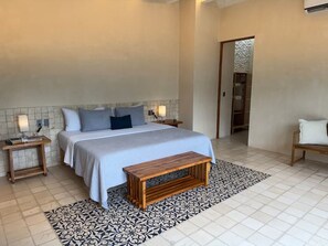 A bedroom with a bed, bedside tables, a bench, and a patterned rug. - Casa Kaban - Centro - C Gastronomico y La Plancha (Centro)