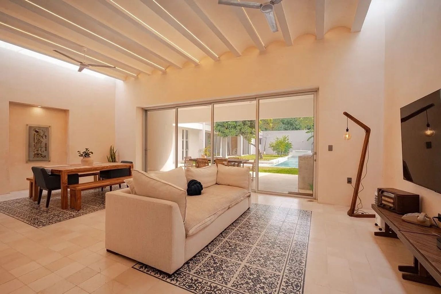 A modern living room with a sofa, a dining table, and a TV.