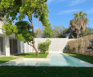 Ein Swimmingpool mit einer klaren, blauen Wasseroberfläche, umgeben von einer gepflegten Rasenfläche und einem Holzzaun.