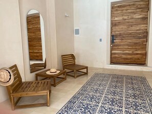 A room with a wooden bench, a small table with a hat, a mirror, and a patterned floor. - Casa Kaban - Centro - C Gastronomico y La Plancha (Centro)