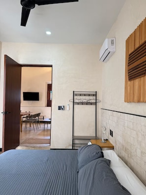 Une chambre d’hôtel avec un lit, un téléviseur fixé au mur, un porte-manteau et un décor mural en panneaux de bois.