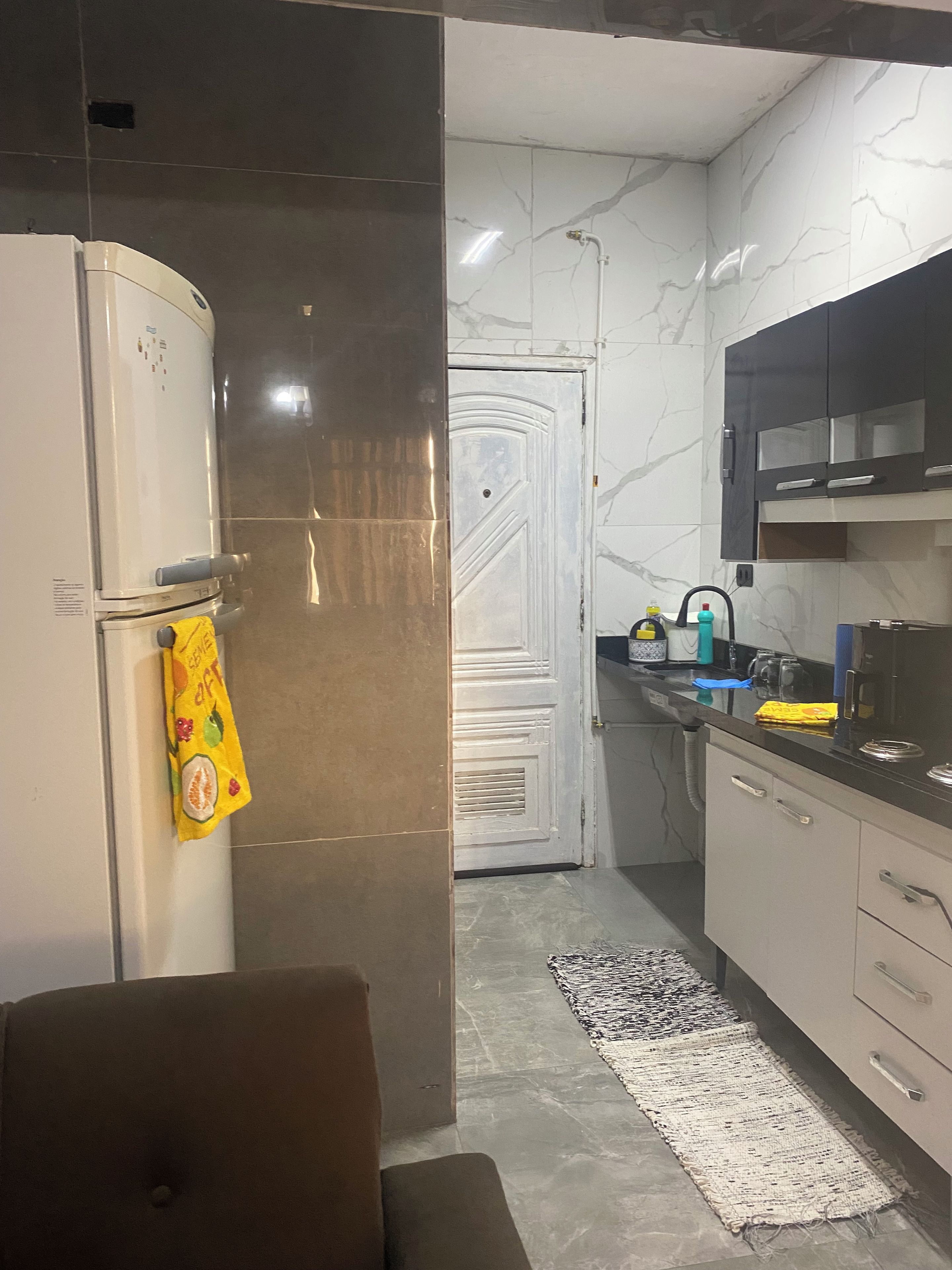 A kitchen with a refrigerator, a microwave, a sink, and cabinets.