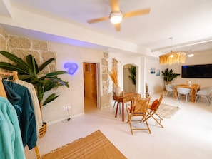 Sala de estar moderna com área de refeições, parede de pedra, planta grande e ventilador de teto.