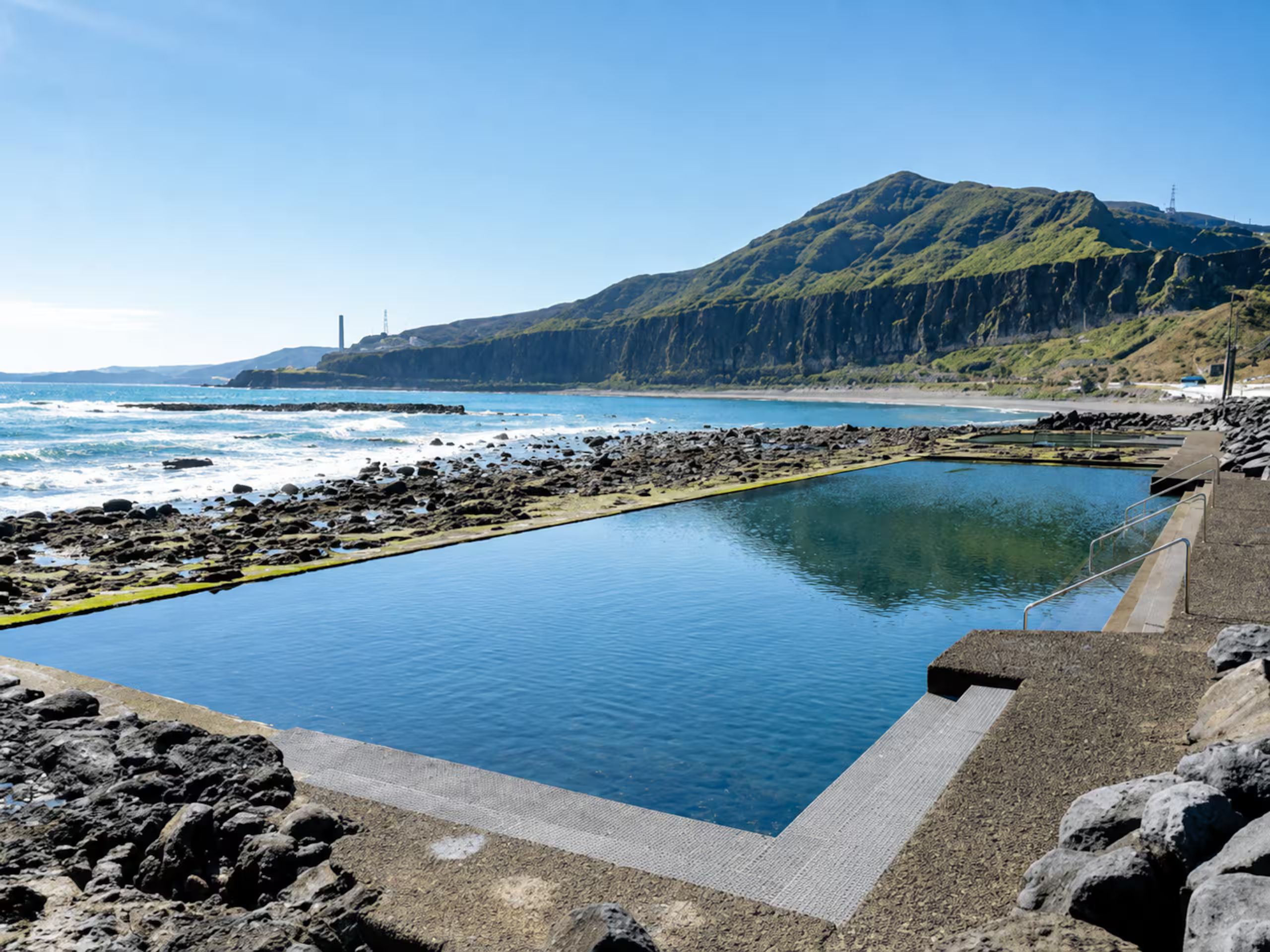 A swimming pool with a view of the ocean and a mountain in the background.