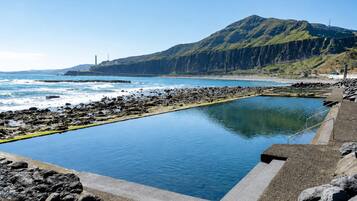 A swimming pool with a view of the ocean and a mountain in the background.