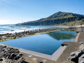 Piscina com vista para o oceano e uma montanha ao fundo.