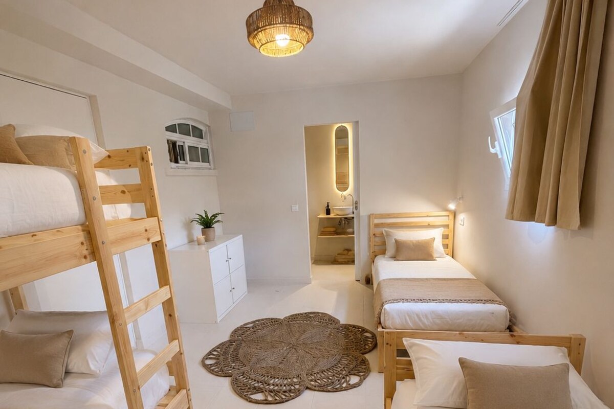 Quarto com beliches, tapete central, espelho e luminária no teto.