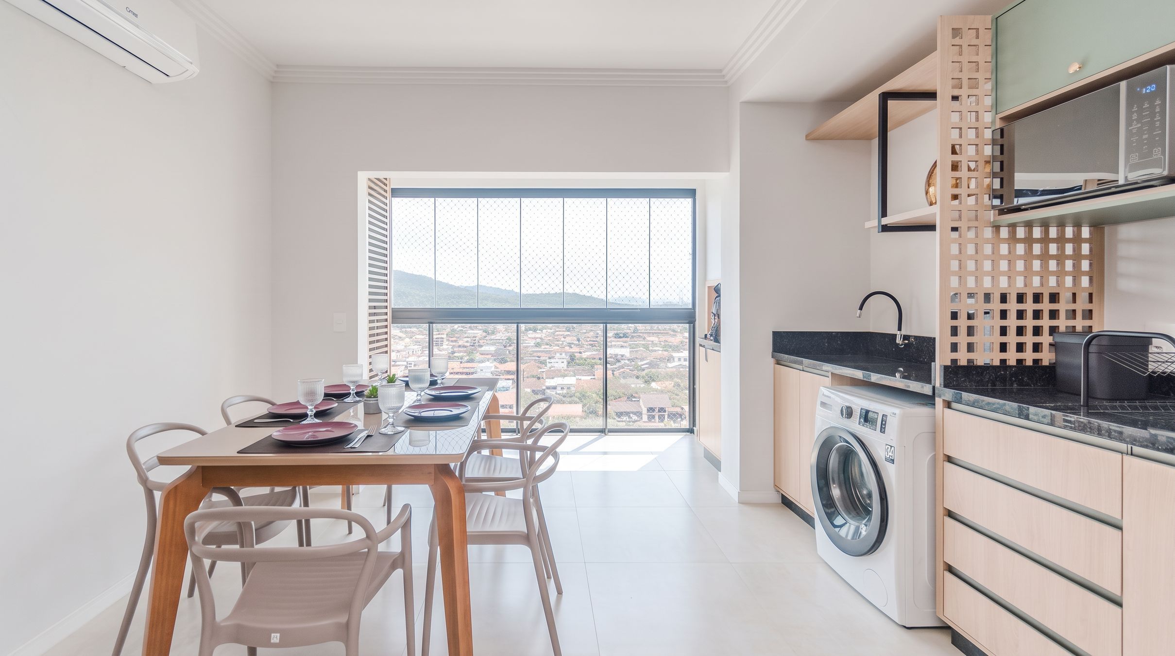 Een praktische keuken met een ingebouwde wasmachine, een eethoek met uitzicht en een groot raam.