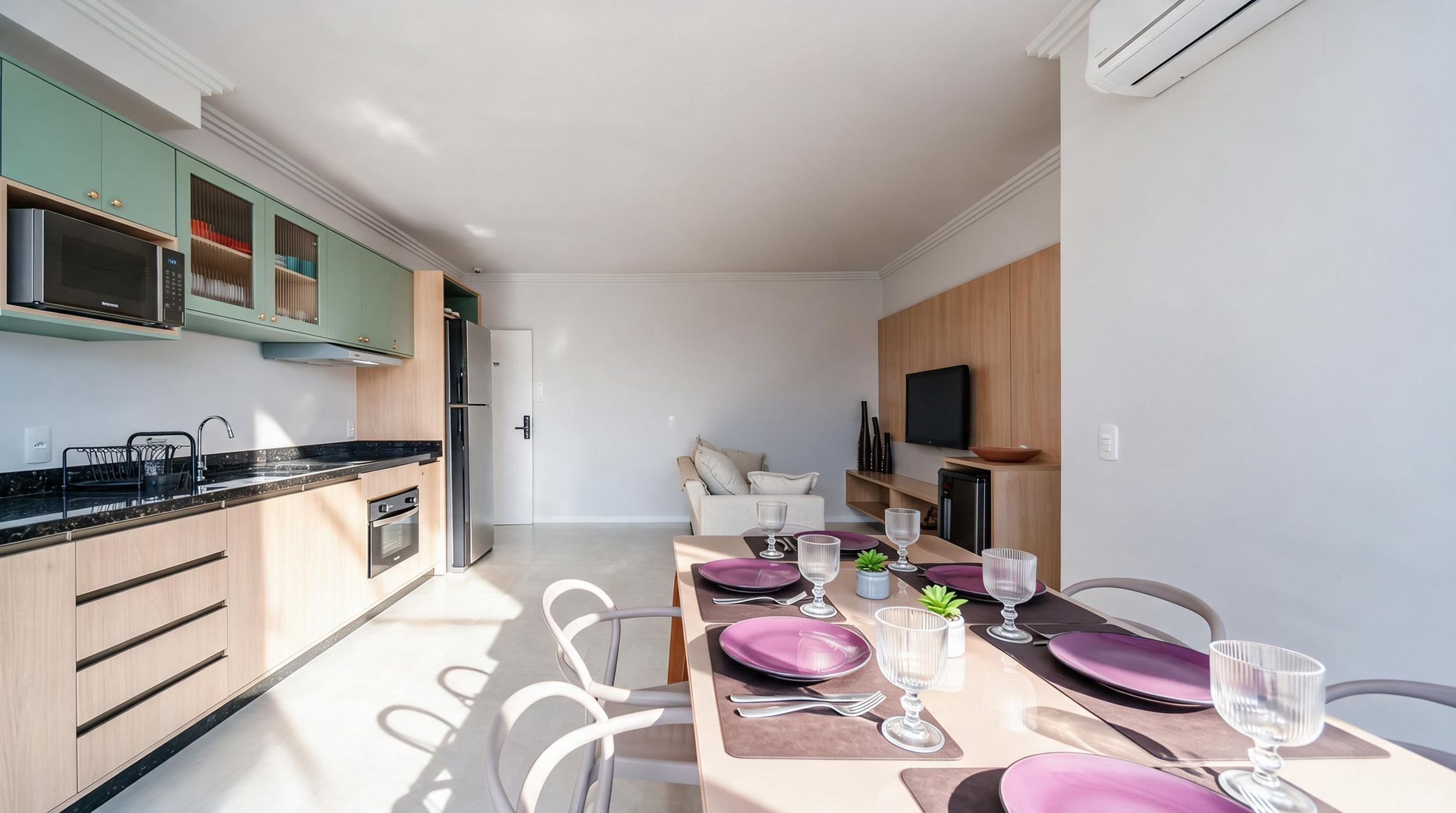 Een moderne keuken met een magnetron, oven en een eethoek met een tafel voor vier personen.