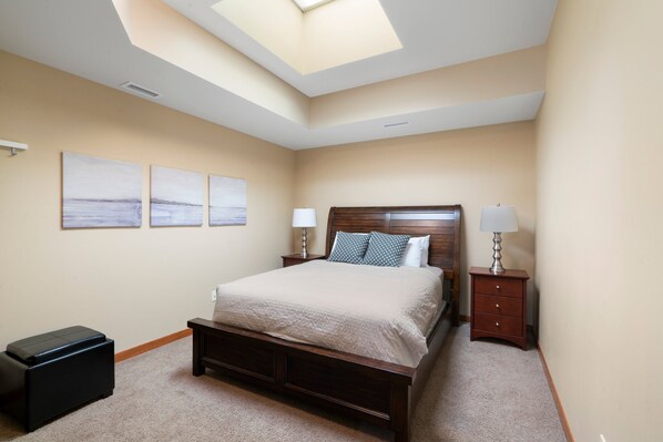 A bedroom with a bed, two nightstands, a lamp, a bench, and three wall art pieces. - This is a test property. Do not book this! (Pattison)