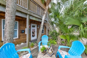 Ein Holzhaus mit Veranda, zwei blaue Adirondack-Stühle und eine Palme.
