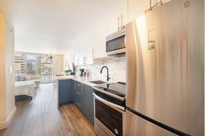 A modern kitchen with a built-in oven, a microwave, and a stainless steel refrigerator. - 1095 Ilikai Marina Modern Studio Near Beach (Honolulu)