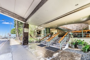 Entrada d'hotel amb un piló de pedra, un senyal de parada i una escala que mena al nivell superior.
