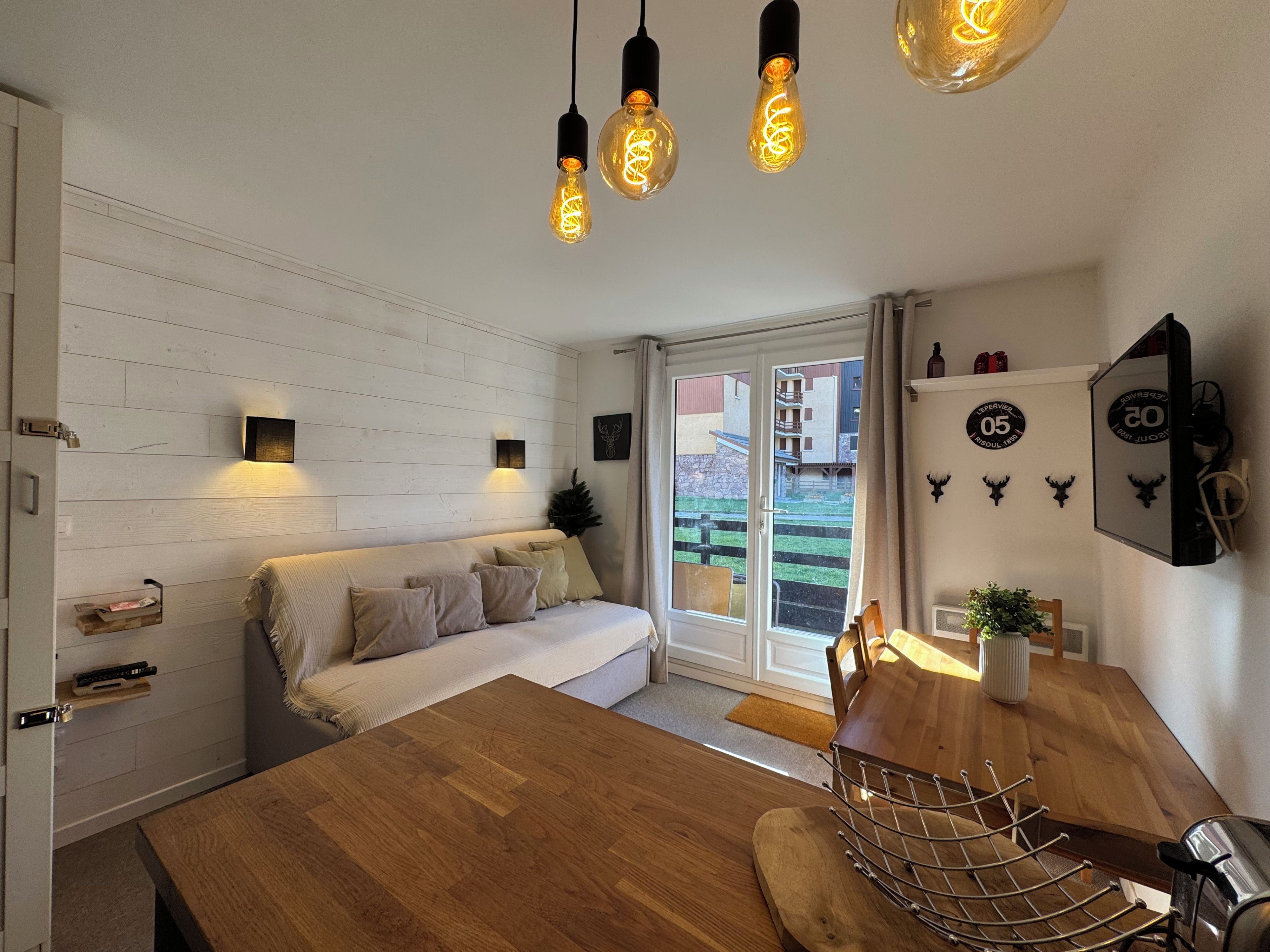 Un espacio de sala acogedor con un sofá, una mesa de comedor de madera e iluminación colgante.