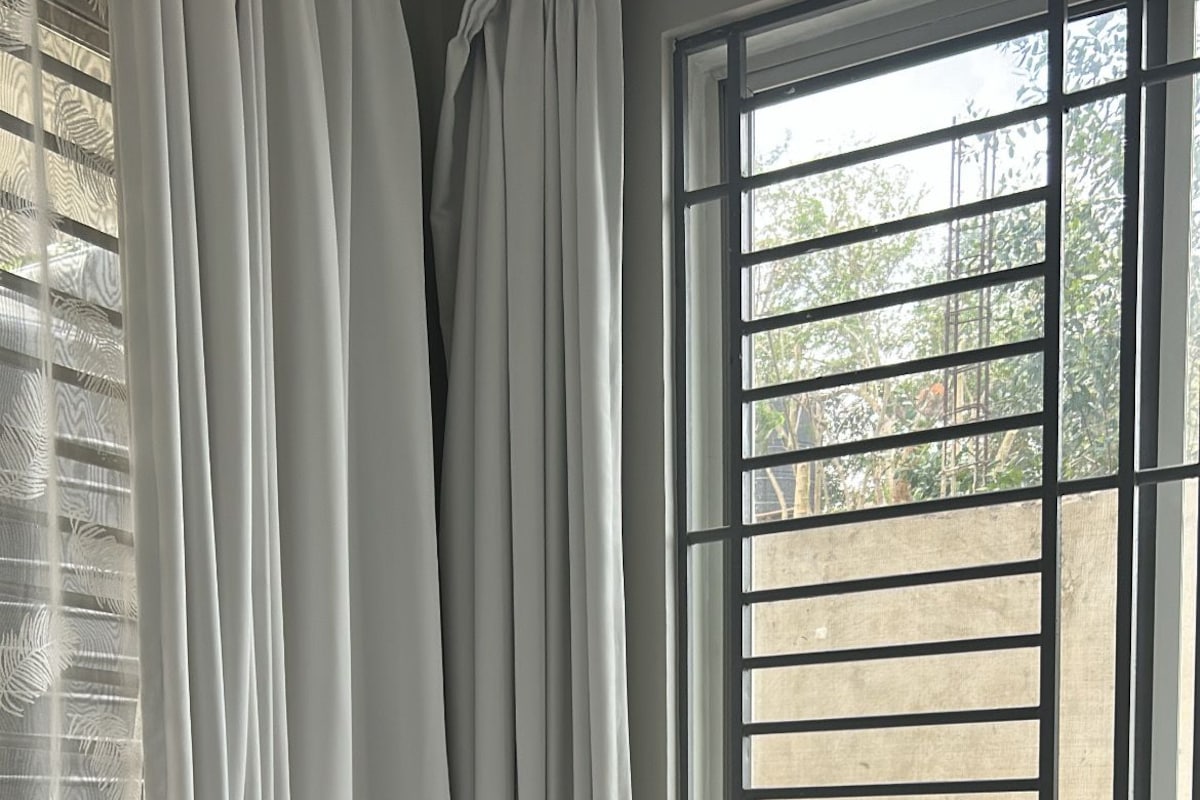 Uma cama com cobertor verde texturizado, travesseiros brancos e um travesseiro rosa.