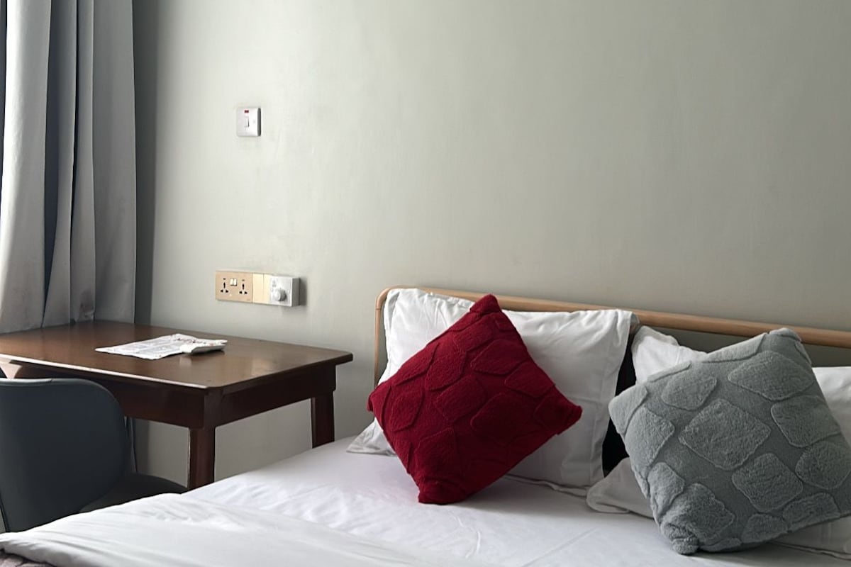 Quarto de hotel com uma cama, uma mesa e um aparelho de ar condicionado.
