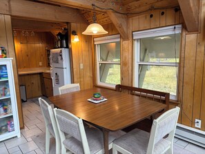 Ein Holzinterieur mit einem Esstisch, Stühlen, einem Kühlschrank und einem Fenster mit Blick.