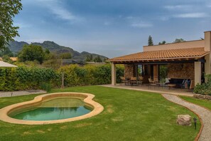 Ein Garten mit Schwimmbecken, Terrassenmöbeln und einer Steinmauer.