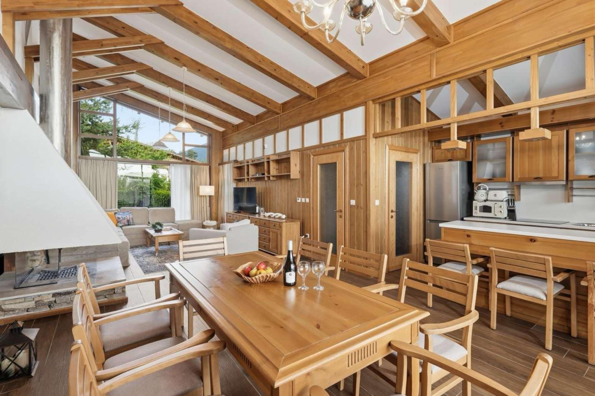 Une cuisine spacieuse avec des meubles de rangement en bois, un coin repas comprenant une table et des chaises en bois, et une grande fenêtre qui laisse entrer la lumière naturelle.