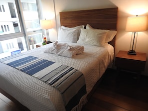 A hotel room with a large bed, two bedside lamps, a window with a view, and a striped throw blanket. - AVA19 Adults Only Villa (Puerto Vallarta)