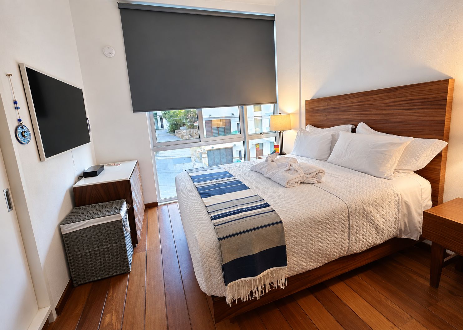 A hotel room with a bed, a TV, a window with a view, and a bedside table.