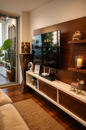 A modern living room with a flat-screen TV mounted on a wooden wall, a white entertainment unit below, and a decorative bull figurine on the right. - AVA19 Adults Only Villa (Puerto Vallarta)