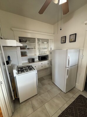 A kitchen with white cabinets, a stove, a microwave, and a refrigerator. - Historic 1-bedroom apartment in charming San Diego neighborhood with AC & Views (San Diego)