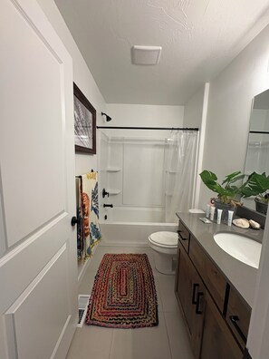 Une salle de bain équipée d’une douche, de toilettes, d’un lavabo et d’un miroir.