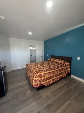 A bedroom with a bed, a dresser, and a door leading to a bathroom. - deluxe motel (Pomona)