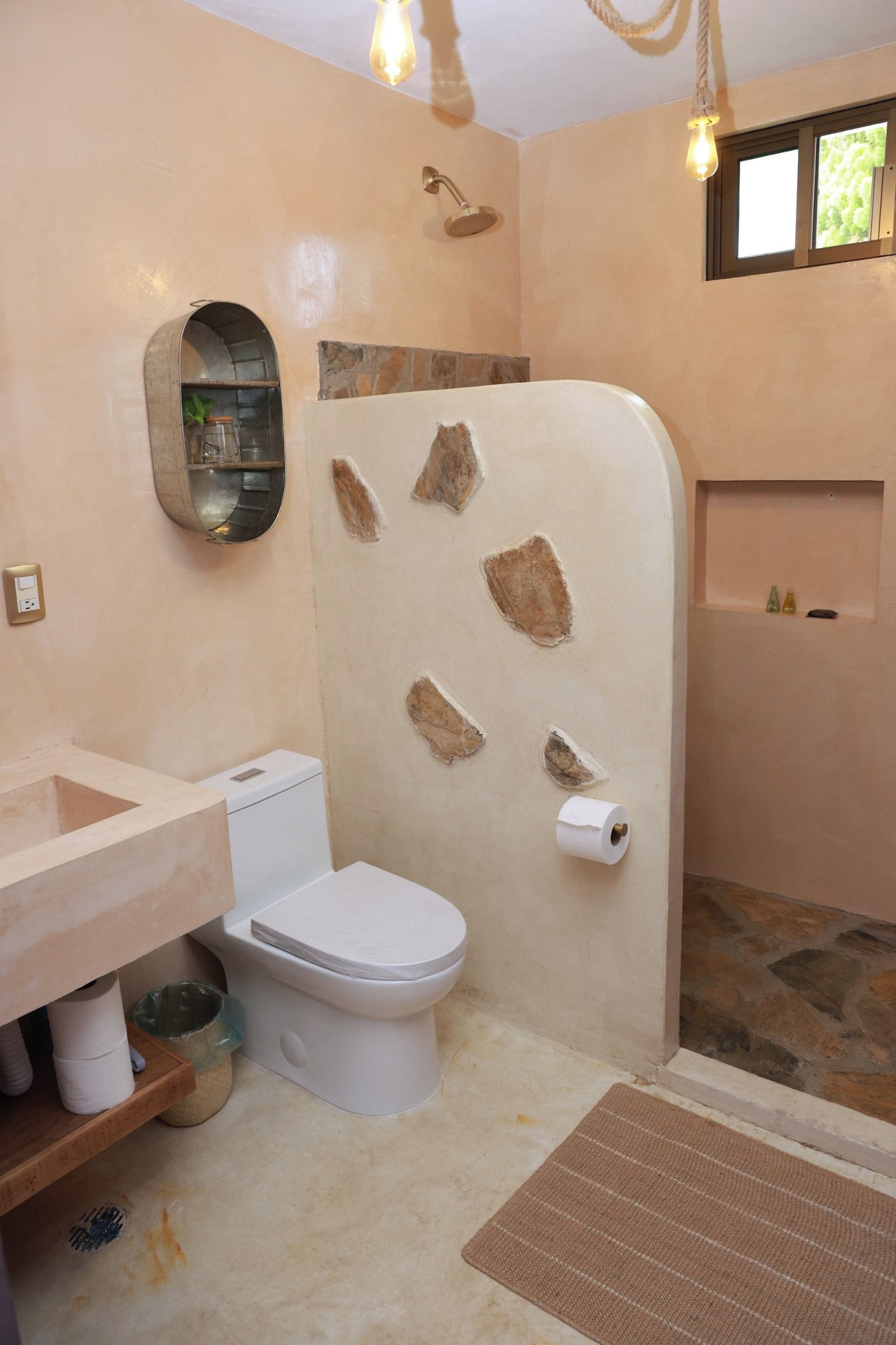 Un baño con inodoro, lavamanos, ducha y una pequeña ventana.