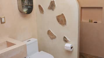 Un baño con inodoro, lavamanos, ducha y una pequeña ventana.