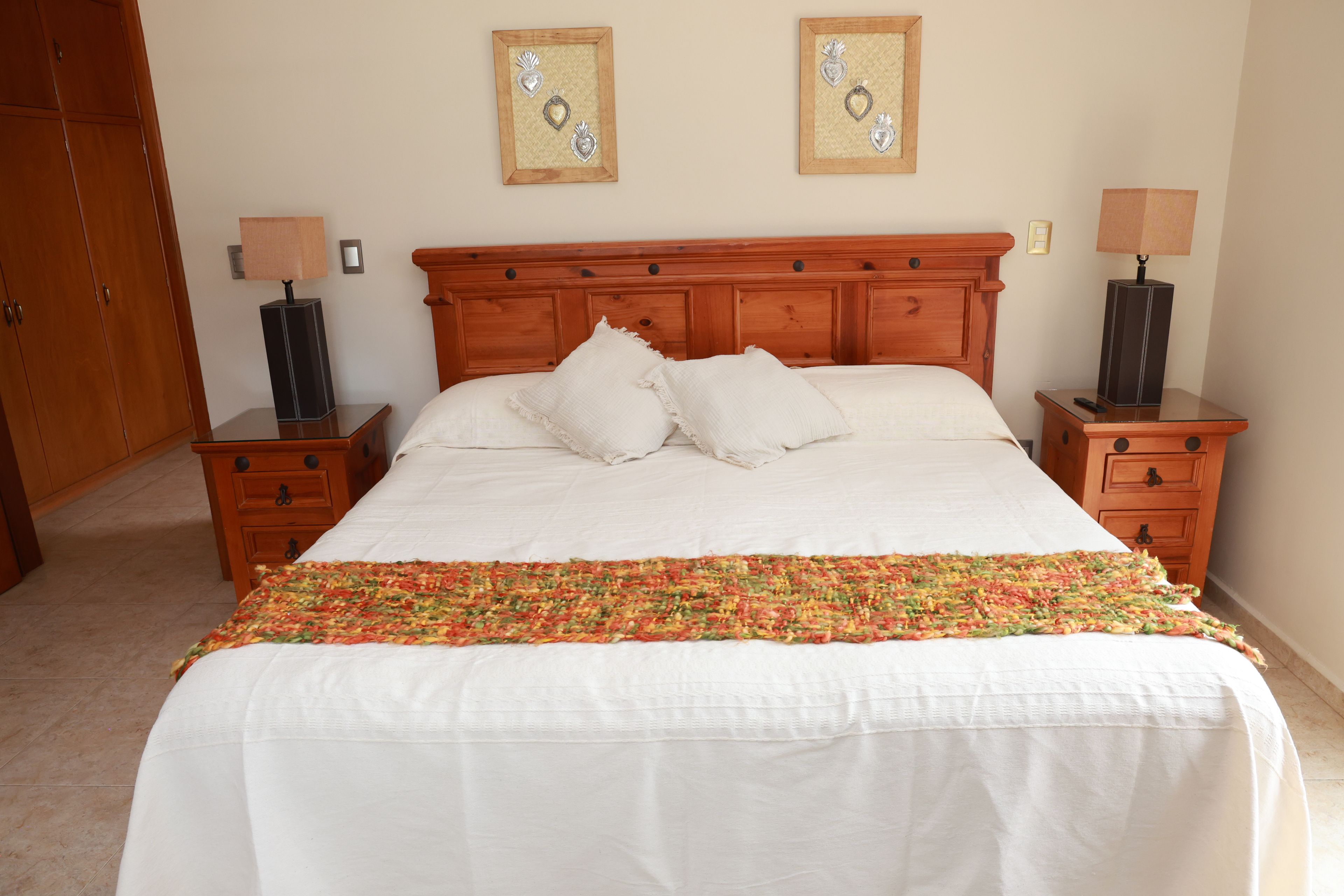 Una habitación de hotel con una cama grande, dos mesitas de noche, un cabecero de madera y dos cuadros colgados en la pared.