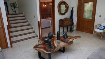 Una sala de estar con una mesa de centro de madera, una escalera, una puerta con panel de vidrio y una silla.