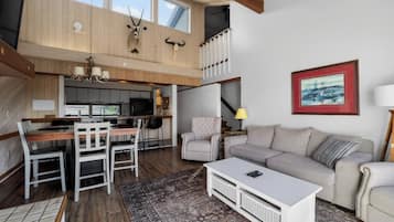 A spacious living area with a dining table, sofa, and a kitchen in the background.