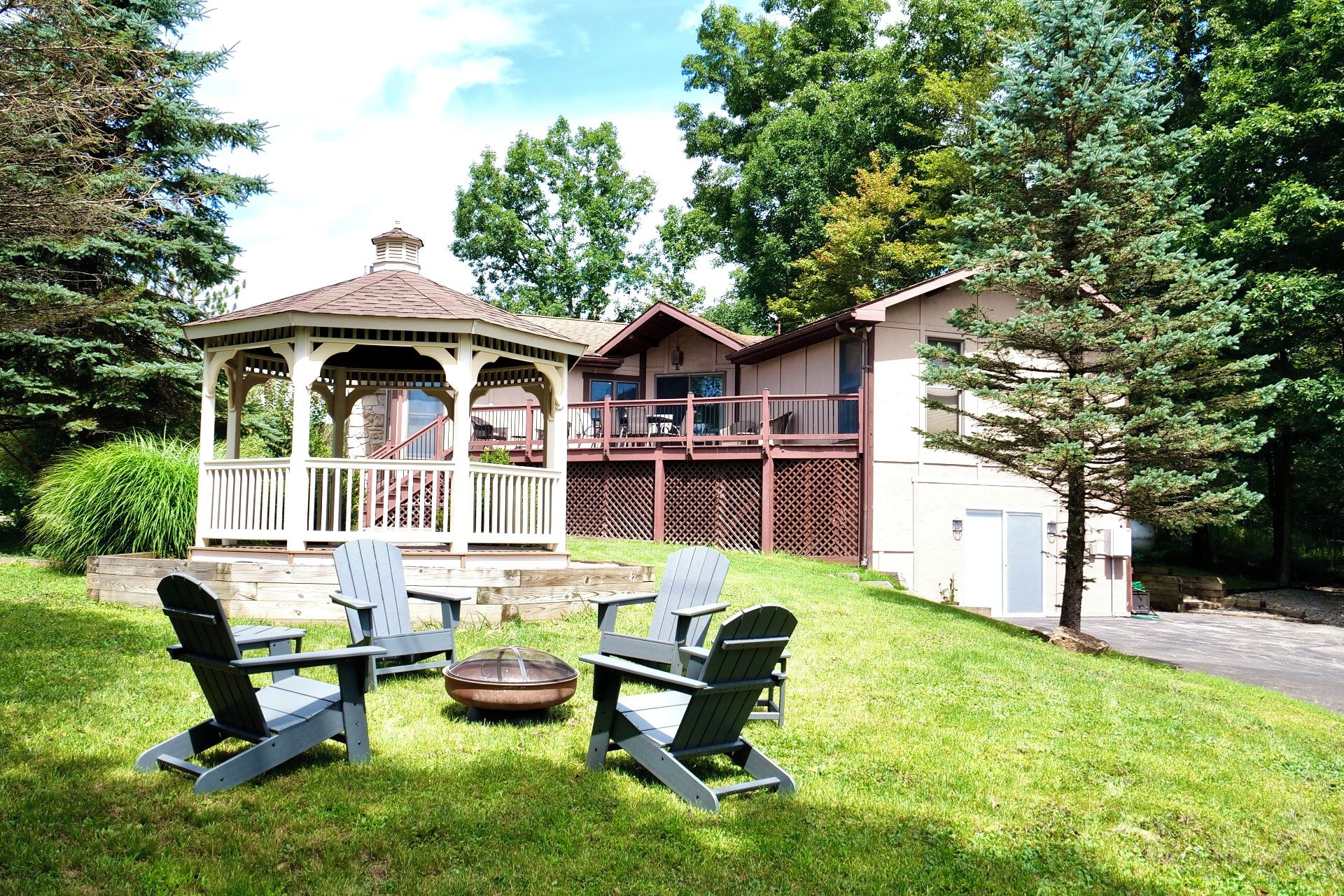 A gazebo with a covered porch, a deck with outdoor furniture, and a house with a fenced yard.