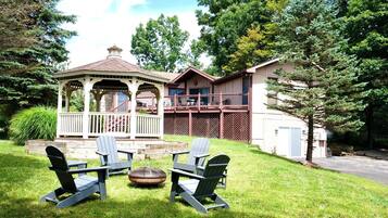 A gazebo with a covered porch, a deck with outdoor furniture, and a house with a fenced yard.