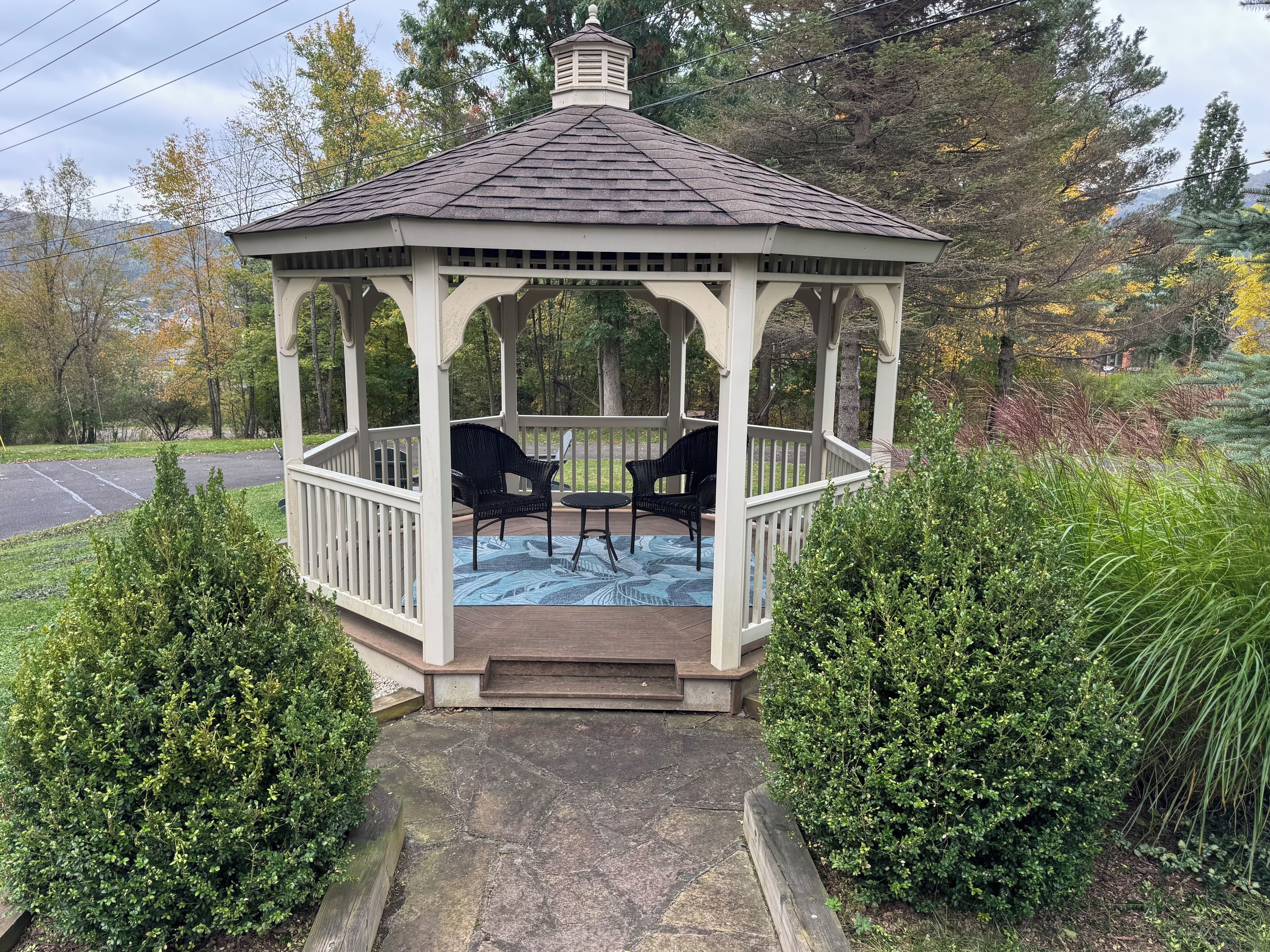 Un gazebo con tetto in tegole, due sedie e un tavolo.