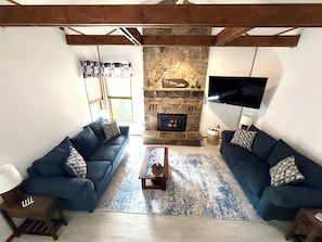 A living room with two sofas, a coffee table, a fireplace, and a television. - Paddle Point Retreat - Mountain & Lake Views - Fire Pit (McHenry)