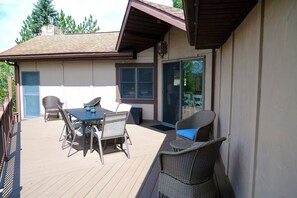An outdoor patio with a table and chairs, a sliding glass door, and a view of the surrounding area. - Paddle Point Retreat - Mountain & Lake Views - Fire Pit (McHenry)