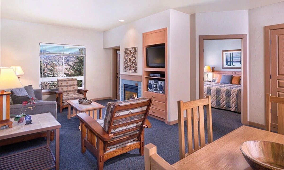 A hotel room with a fireplace, a television, a bed, and a view of the outdoors.