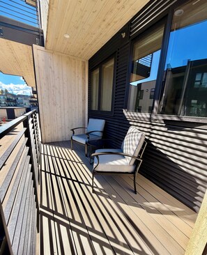 Een houten terras met een zithoek, inclusief een tafel en twee stoelen.