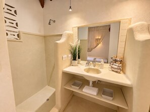 Ein Badezimmer mit Waschbecken, Spiegel, Handtuchhalter und Duschbereich.