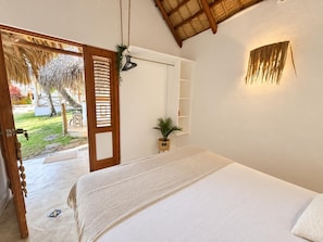 Ein Schlafzimmer mit einem Bett, einer Holztür, einer kleinen Pflanze und einem Regal.