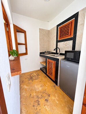 Eine kleine Küche mit Gasherd, Mikrowelle und Kühlschrank.